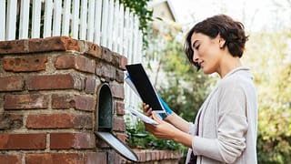 Woman sorting through mail at her mailbox mbL.width