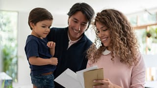 Young family smiles while looking through mai.width YCkchbc