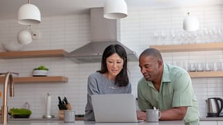 couple staring at computer in kitchen