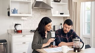 couple talking over papers in kitchen KRXubp.width