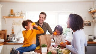 family unpacking groceries in kitchen.width