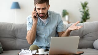 man on couch on phone call near laptop gfF.width .jpg