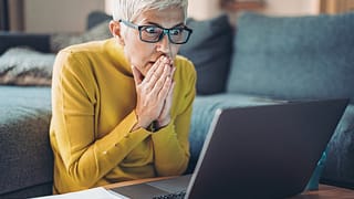 mature woman looking at computer in shock