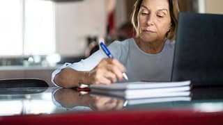 older woman taking notes laptop gettyimages