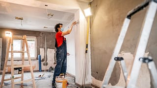 person putting up drywall in home renovation .width