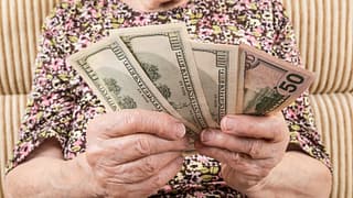 senior woman holding cash money bills social security cola retirement getty