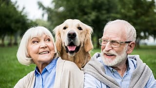 smiling senior couple looking at adorable dog