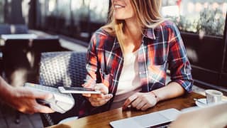 woman in restaurant paying with smart phone a.width