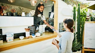 woman paying food truck owner with credit car.width aTVnc.jpg