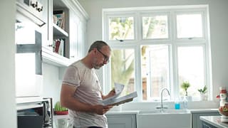 worried man in kitchen with bills fEoJV.width