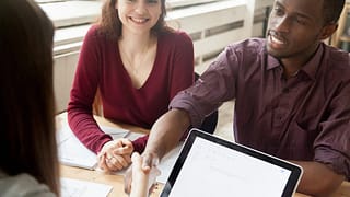 Couple shaking hands over paperwork at a desk.width jzUDgFs.jpg