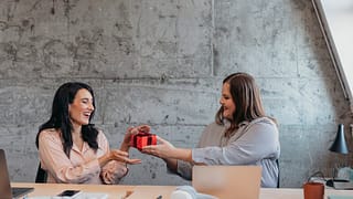 Female gives friend wrapped gift in an office.width JBnNnN.jpg