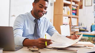 Man reading paperwork at desk UyTBhM.width .jpg