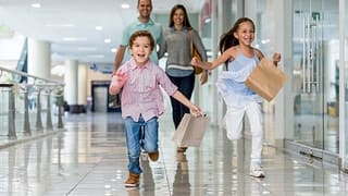 Parents and kids at shopping mall with shoppi.width GYqrug.jpg