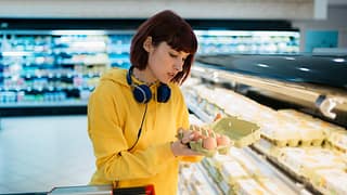 Shopper inspecting a carton of eggs in the gr.width .jpg