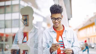 Teen boy using his phone and holding a credit.width .jpg
