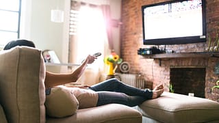 Woman lounging on her sofa watching tv hUjj.width .jpg