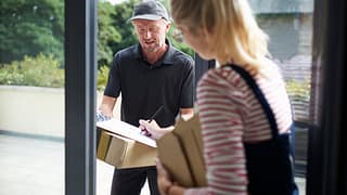 Woman signing for packages with a delivery pe.width VWyGgX.jpg