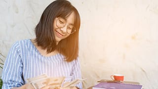 Young woman smiling as she counts cash in her.width XDyly.jpg