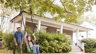dad pushing daughter in swing in front yard.width .jpg