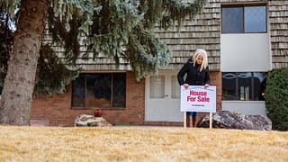 person in front of house with for sale sign S.width .jpg