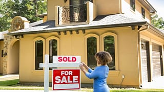 person putting sold sign in front of house T.width .jpg