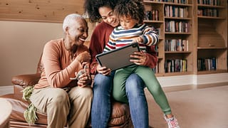 two adults and a child looking at a tablet and smiling.jpg