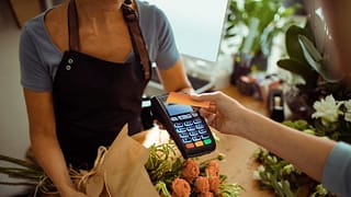 woman holding credit card over payment reader.width IAlpwc.jpg