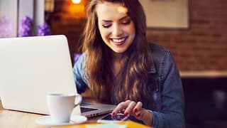 woman smiling with coffee and computer vkYiv.width .jpg