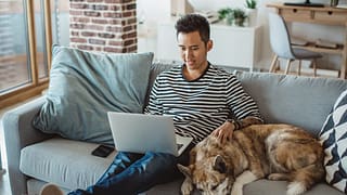 young man on laptop on couch with dog QRysiD.width .jpg