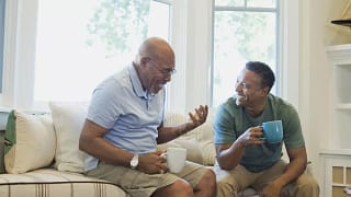 Cheerful father and son having coffee on sofa.width .jpg