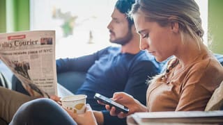 Couple sits together while one reads a newspa.width HSHgLW.jpg