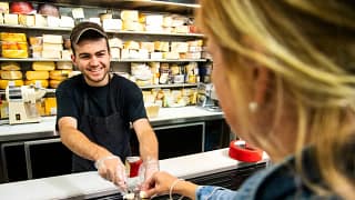 Employee handing sample of cheese to woman sh.width QAGKAOI.jpg
