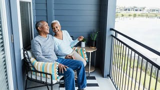Happy mature couple sitting on balcony overlo.width gFthua.jpg