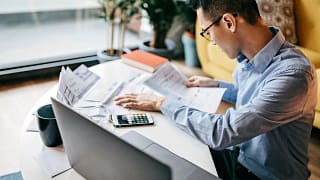 MAn using a calculator and looking over docum.width bFwUjX.jpg