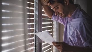 Man looks saddened by paper that hes reading .width .jpg