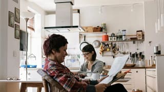 Two people in a kitchen reading the news toJ.width .jpg