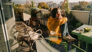 Woman sitting outside on her condo balcony Hq.width .jpg