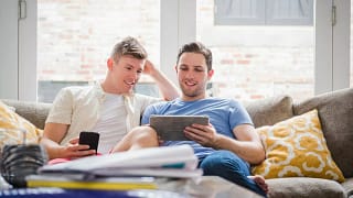 Young couple sit on sofa and look at tablet .width .jpg