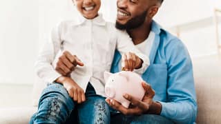 dad daughter put money in piggy bank.width .jpg
