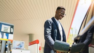 person filing up their car with gas AhVsk.width .jpg
