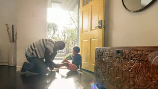 person putting on childs shoes at front door .width hxnClq.jpg