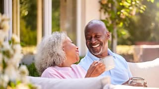 two older people sitting outside drinking coffee and smiling.jpg