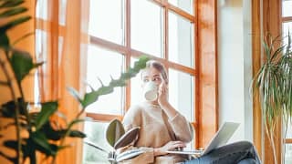 woman with coffee and laptop looking out wind.width .jpg