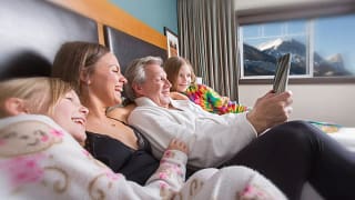 Family relaxing in bed looking at a tablet wi.width kMhkkJd.jpg