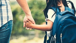 Parent and child in backpack holding hands.width .jpg
