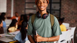 a person with a backpack and headphones around their neck holding a laptop gettyimages .jpg