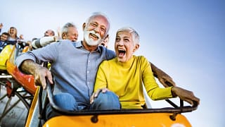 carefree seniors having fun on rollercoaster at amusement park.jpg