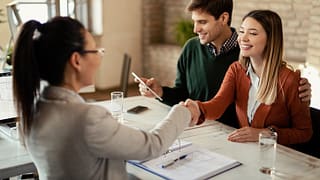 couple signing mortgage and shaking hands wit.width .jpg