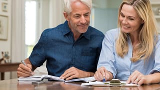 mature couple discussing finances with pens and paper.jpg
